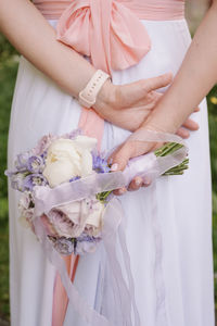 Midsection of bride with bouquet