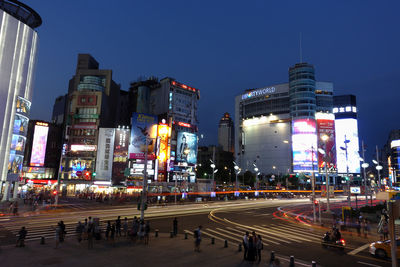 Illuminated city street and buildings against sky at night