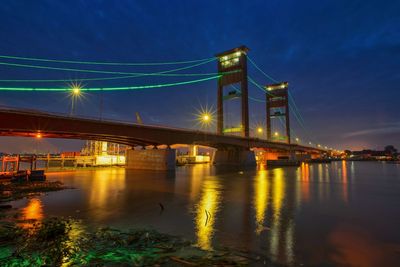 Illuminated suspension bridge over river at night