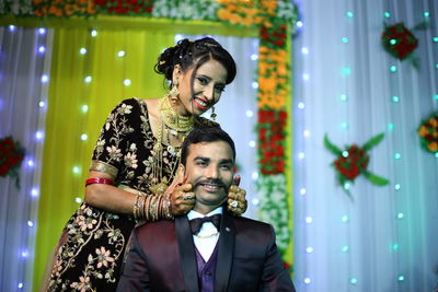 Portrait of happy bride holding groom cheeks during wedding ceremony