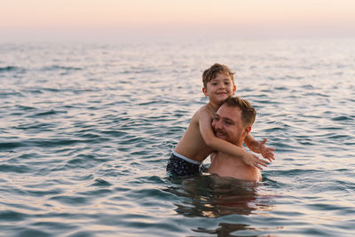 Portrait of young woman swimming in sea during sunset