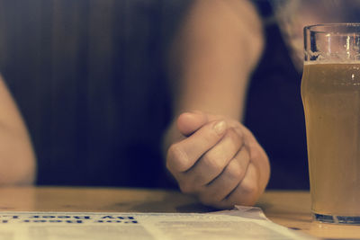 Close-up of hand holding drink on table