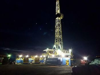 Low angle view of illuminated communications tower at night