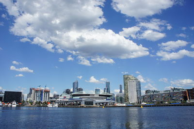 City at waterfront against cloudy sky