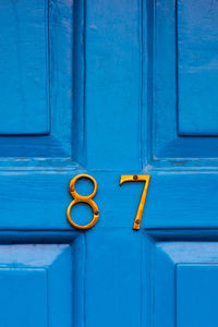 House number 87 on a blue wooden front door in london 