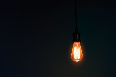 Close-up of illuminated light bulb against black background