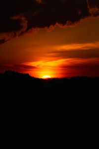 Silhouette landscape against dramatic sky during sunset