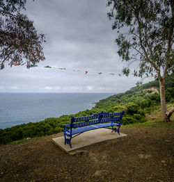 Scenic view of bench facing sea against sky