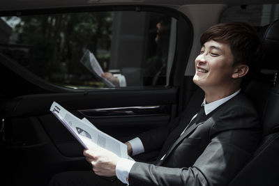 Side view of man using mobile phone in car