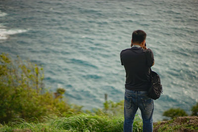 Rear view of man standing against sea