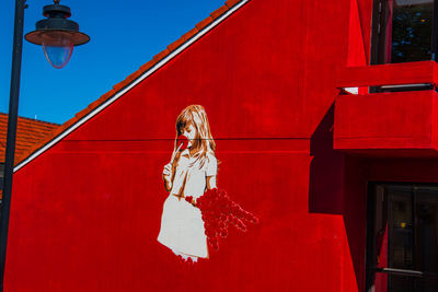 Portrait of woman standing against red wall