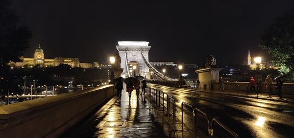 Illuminated bridge over river in city at night