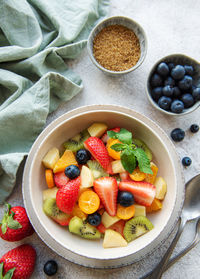 Healthy fresh fruit salad in a bowl on concrete background