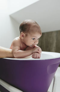 Cropped hand of mother bathing son in bathtub at home