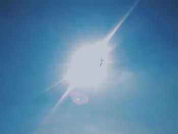 Low angle view of sun shining through clouds