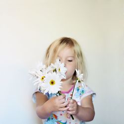 Close-up of girl holding flower over white background