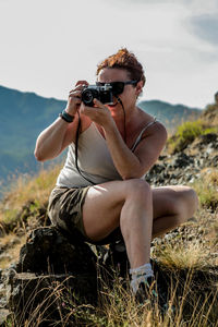 Midsection of woman photographing on field