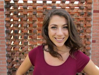 Portrait of smiling teenage girl against brick wall