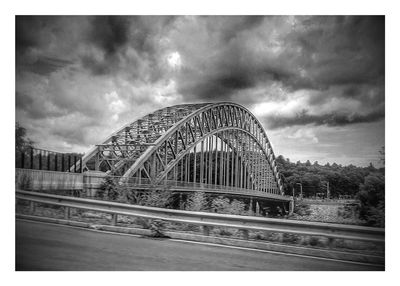 Bridge over river against cloudy sky