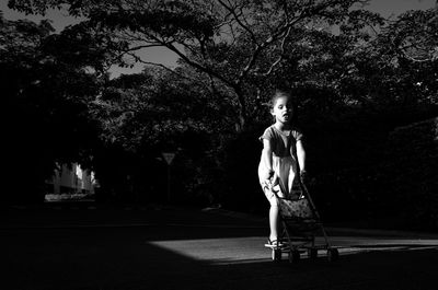 Full length portrait of girl standing against trees