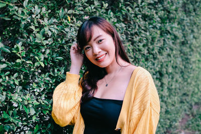 Close up of young pretty asian woman in blue yellow sweater with garden background.