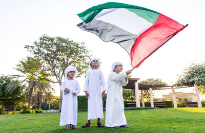 Children with united arab emirates flag standing on grassy field