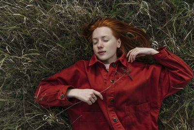 Young woman with eyes closed lying on grass field