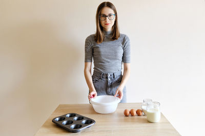 Woman in t-shirt and jeans preparing homemade cupcakes in her kitchen