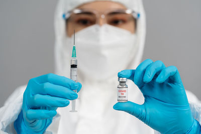Midsection of doctor holding syringe against white background