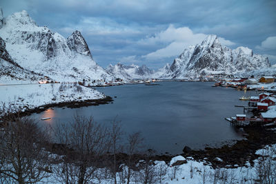 Frozen lake by snowcapped mountain against sky