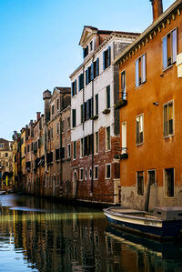 Buildings by canal against sky in city