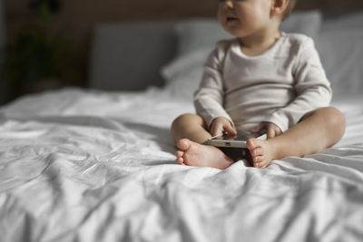 Boy using mobile phone while lying on bed at home