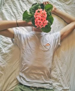 High angle view of man with flowers on face lying down on bed
