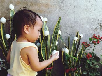 Side view of cute girl holding egg shell by flowering plants