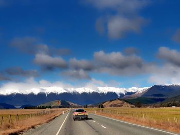 Cars on road by mountain against sky