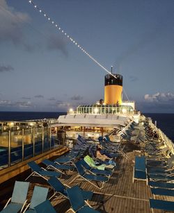 Illuminated ship by sea against sky at dusk