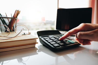 Close up businesswoman using calculator and laptop for do math finance on wooden desk in office