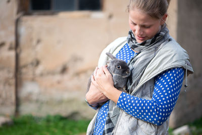 Mid adult woman carrying rabbit while standing in park