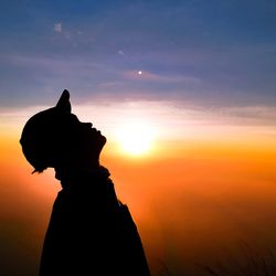 Silhouette man looking up against sky during sunset