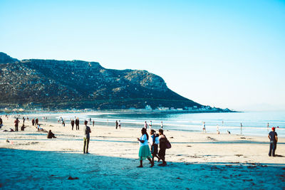 People on beach against clear sky