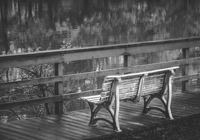 Chairs and table by railing against trees