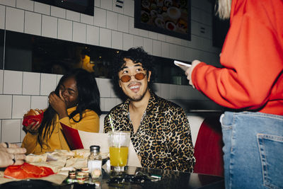 Midsection of waitress taking order from cheerful male and female friends in cafe