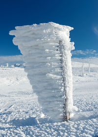 Close-up of snow covered land against blue sky