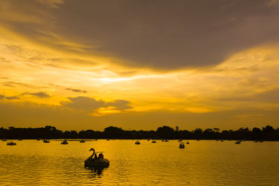 Silhouette boats in sea against sky during sunset