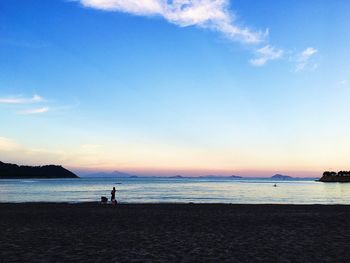 Silhouette person on beach against sky during sunset