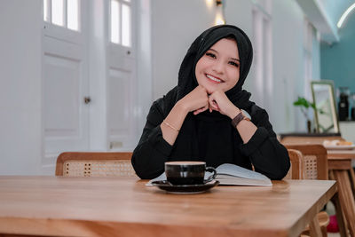 Young woman using mobile phone while sitting on table