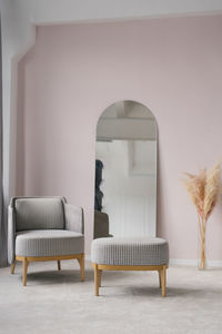 Classic modern grey armchairs, ottoman, mirror, pampas grass dried flowers in a vase in living room