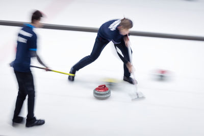 Blurred motion of people playing curling