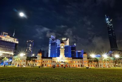 Illuminated buildings in city against sky at night