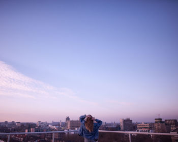 Rear view of woman photographing against cityscape